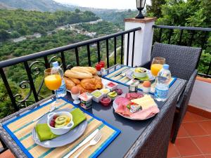una mesa de desayuno con comida y bebida en el balcón en Villa Morera Bed & Breakfast, en Frigiliana