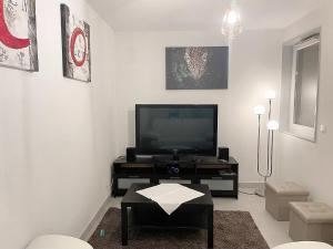 ein Wohnzimmer mit einem Flachbild-TV und einem Tisch in der Unterkunft LE VELODROME Chic appartement in Marseille