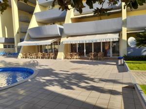 a building with a patio with a pool and tables and chairs at Condominio do Mar in Lagos
