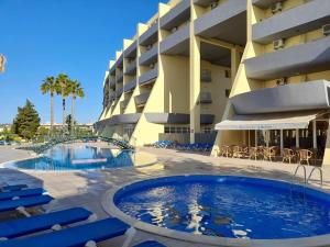a resort with a swimming pool and chairs and a building at Condominio do Mar in Lagos