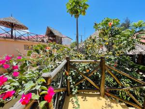 a wooden walkway with flowers and a fence at Max Hotel Nungwi in Nungwi