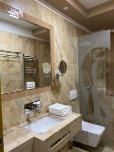 La salle de bains est pourvue d'un lavabo, d'un miroir et de toilettes. dans l'établissement New W Hotel, à Tirana