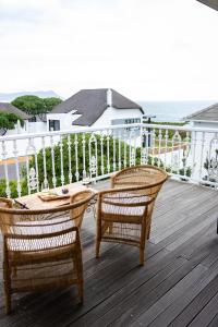 dwa krzesła i stół na tarasie z oceanem w obiekcie Villa Le Roc Kleinmond Accommodation w mieście Kleinmond