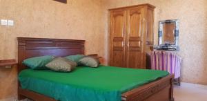 1 dormitorio con cama verde y cabecero de madera en Brothers house 4, en Imsouane