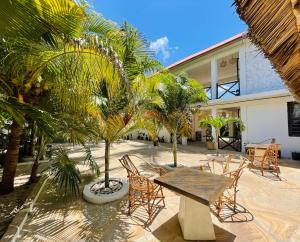 a patio with chairs and a table and palm trees at Max Hotel Nungwi in Nungwi