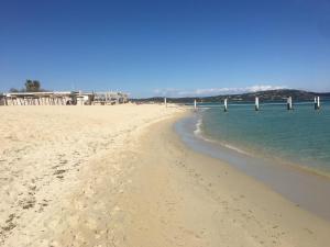 a sandy beach with a pier in the water at Clos des Vignes Pampelonne Vineyard in Ramatuelle