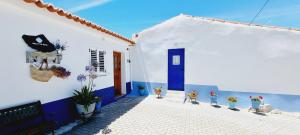 a white house with blue doors and potted plants at Aqui n' al-deia in Mértola