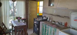 a kitchen with a stove and a sink and a table at El Paraiso de Carmen de Areco in Carmen de Areco