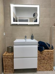 ein Badezimmer mit einem weißen Waschbecken und einem Spiegel in der Unterkunft ZEITLOS in Velden in Velden am Wörthersee