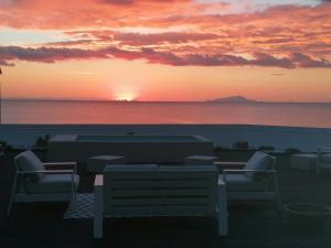 a sunset over the ocean with chairs and tables at La Chiaja art&relais in Castellammare di Stabia