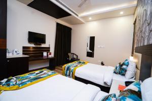 um quarto de hotel com duas camas e uma televisão em The Golden Apple em Lucknow