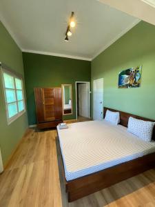 um quarto com uma cama grande num quarto com paredes verdes em Residencial Avenida Geovanni em São Tomé