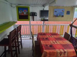 balcón con mesa, sillas y TV en La kaz créole, en Bouillante