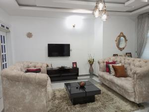 salon z 2 kanapami i telewizorem w obiekcie E - Glisters Home w Warri