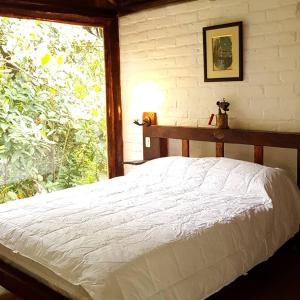 1 dormitorio con cama blanca y ventana en La Penal Amazon Lodge!, en Mera