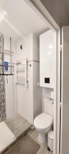 La salle de bains blanche est pourvue d'une douche et de toilettes. dans l'établissement Cosy appartement dans une villa avec piscine, proche du centre et de la mer, à Cabourg