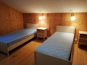 two beds in a room with wooden walls and wooden floors at Ostello SanMartino in San Martino di Castrozza