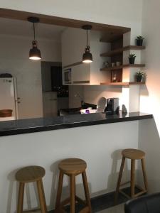 een keuken met 3 barkrukken en een aanrecht bij Apartamento na Enseada com vista para o mar - 300 m da praia in Guarujá