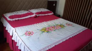 Una cama rosa y blanca con flores. en Loft super charmoso no centro de Nova Friburgo en Nova Friburgo