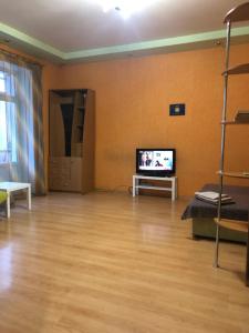 a living room with a tv and a wooden floor at Квартира-студия на Котляра in Kharkiv