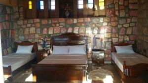 - une chambre avec 2 lits et un mur en pierre dans l'établissement maison d'hôtes yamine, à Béni Mellal