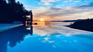 a swimming pool with a sunset in the background at Holiday Hvar in Vrbanj