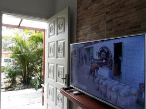 TV de pantalla plana sentada en una mesa junto a una puerta en KITNET UBA com ar condicionado en Ubatuba