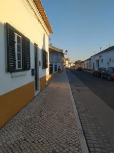 a cobblestone street next to a building with windows at Casa do Limoeiro in Golegã
