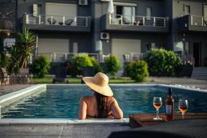 a woman in a hat sitting in a swimming pool at Isola Apartments in Xylokastron
