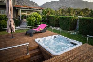 a hot tub on a wooden deck with a chair at Isola Apartments in Xylokastron