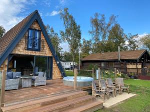 a house with a deck with a table and chairs at Widgeon Bespoke Cabin is lakeside with Private fishing peg, hot tub situated at Tattershall Lakes Country Park in Tattershall