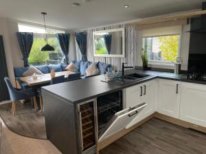 a kitchen and living room with a blue couch at Indulgence Lakeside Lodge i3 with hot tub, private fishing peg situated at Tattershall Lakes Country Park in Tattershall