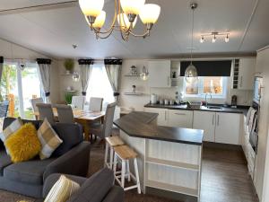a kitchen and living room with a couch and a table at Indulgence Lakeside Lodge i2 with hot tub, private fishing peg situated at Tattershall Lakes Country Park in Tattershall