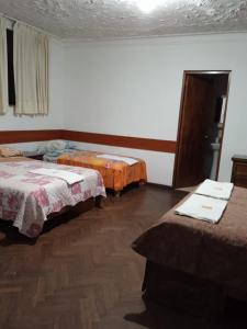 a room with two beds and a wooden floor at Hospedaje Schell in Lima