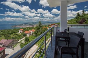 einen Balkon mit einem Tisch und Stühlen sowie Blick auf das Wasser in der Unterkunft Velestovo View Apartments in Ohrid