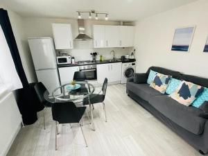 a living room with a black couch and a glass table at Enfield Chase Apartment in Enfield