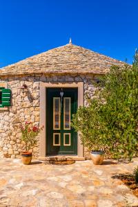 una casa de piedra con una puerta verde y algunas plantas en Island Getaway - Heritage House with heated pool, en Mirce