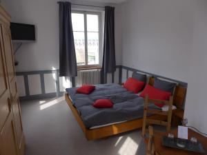 Un dormitorio con una cama con almohadas rojas y una ventana en Hôtel-Restaurant de la Gare, en Glovelier