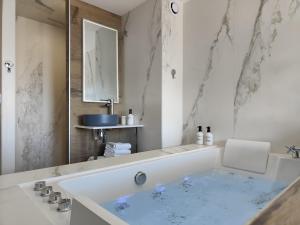 a white bathroom with a tub and a mirror at Suites JM - Les Pins Marines - Jacuzzi & Vue Mer in Bandol