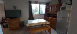 eine Küche mit einem Tisch, einem Kühlschrank und einem TV in der Unterkunft Idéal pour les vacances in Selonnet