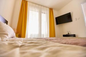 a bedroom with a bed and a window with yellow curtains at STARLIGHT BRONZE Szeged- Exclusive in Szeged