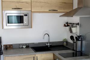 a kitchen with a sink and a microwave at One One Five Apartment - Free Parking in Swansea +8 photos