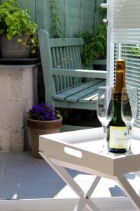 One One Five Apartment في سوانسي: طاولة بيضاء مع زجاجة من الشمبانيا وكأس من النبيذ