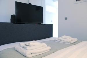a pile of towels sitting on a bed with a tv at One One Five Apartment - Free Parking in Swansea