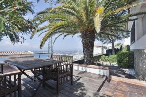 een tafel en stoelen op een balkon met een palmboom bij House vista bella in Roses