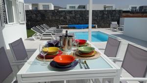 een witte tafel met kommen en borden op een patio bij VILLA TRAFALGAR, magnífica casa en la costa ideal para familias que buscan tranquilidad in Playa Blanca