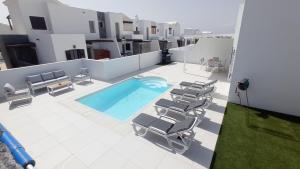 a pool on the roof of a building with lounge chairs at VILLA TRAFALGAR, magnífica casa en la costa ideal para familias que buscan tranquilidad in Playa Blanca