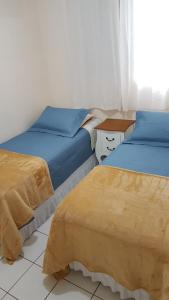 two beds sitting next to each other in a room at Apartamento TOP CLIMATIZADO em CRICIÚMA-SC - ótimo CUSTO-BENEFÍCIO - Cozinha completa - Cama Box - WiFI - Smart TV - Apps YouTube - NetFlix - Prime Vídeo - Garagem coberta - Portaria Digital 24h - Lugar sossegado e arborizado - Acomoda até 5 pessoas in Criciúma