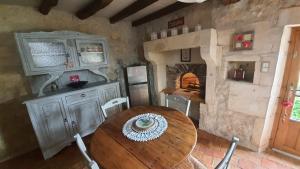 a dining room with a wooden table and a fireplace at La Charmentaise in Saint-Sulpice-de-Cognac