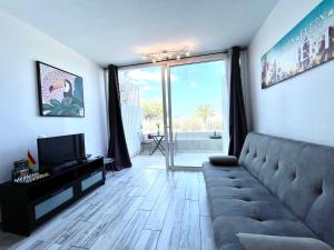 un soggiorno con un divano e una televisione di Oasis Costa del Silencio a Costa Del Silencio